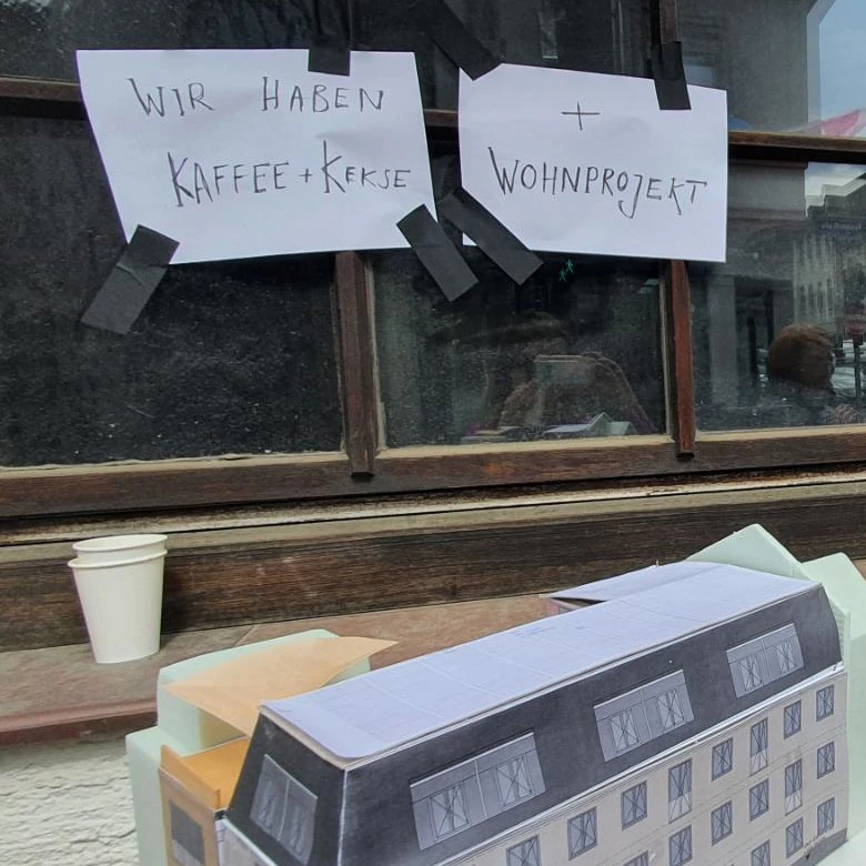 Plakat mit der Aufschrift 'Wir haben Kaffee und Kekse und Wohnprojekt'